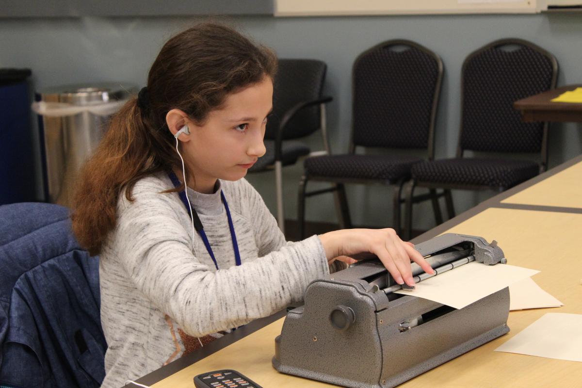 Girl writing on Perkins brailler