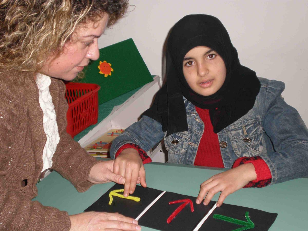Student with a head scarf uses board with arrows.