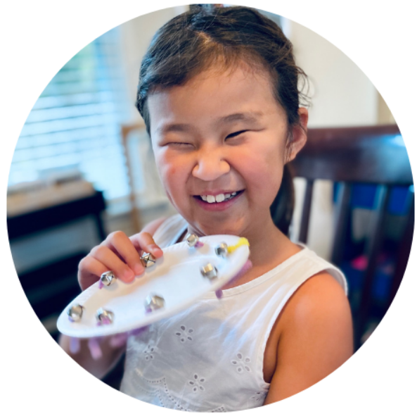 NFB BELL Academy picture of a young girl enjoyinig a hand made instrument with bells and a paper plate