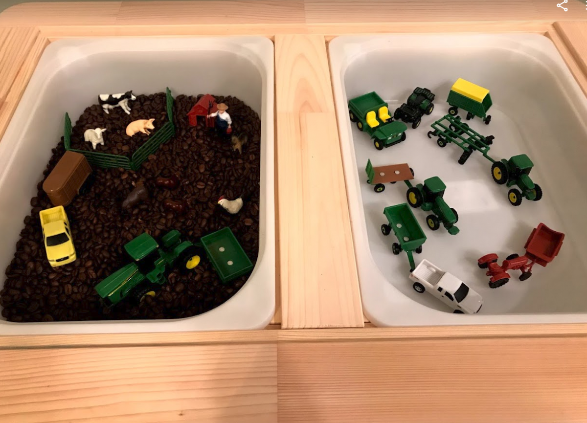 farm sensory bin with small plastic animals and tractor toys in a bin filled with dried beans
