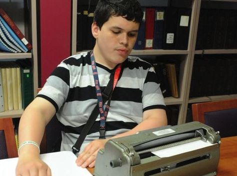 student in striped shirt reading braille