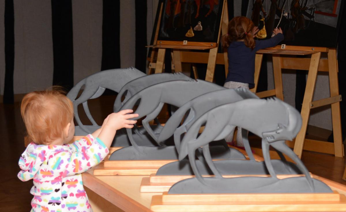 A young girl touches carved wolves