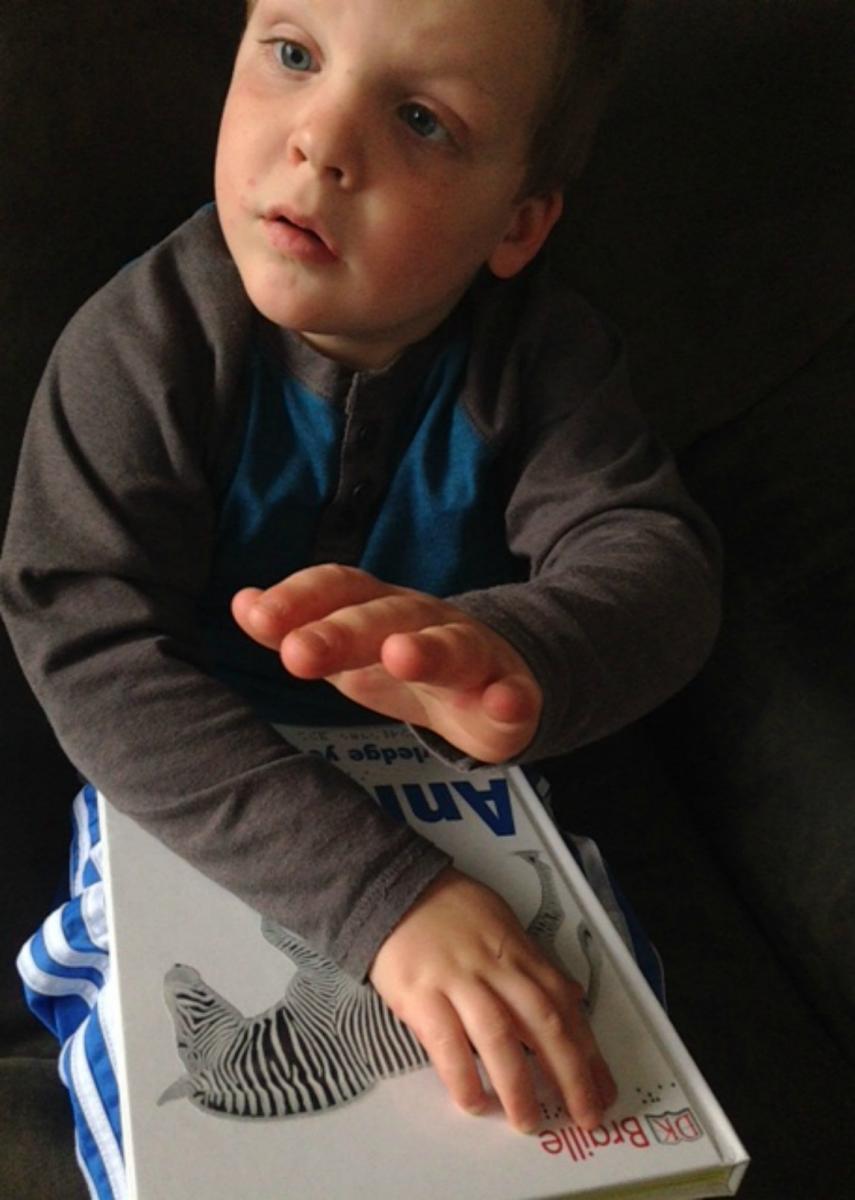 A young boy signs as he reads the book