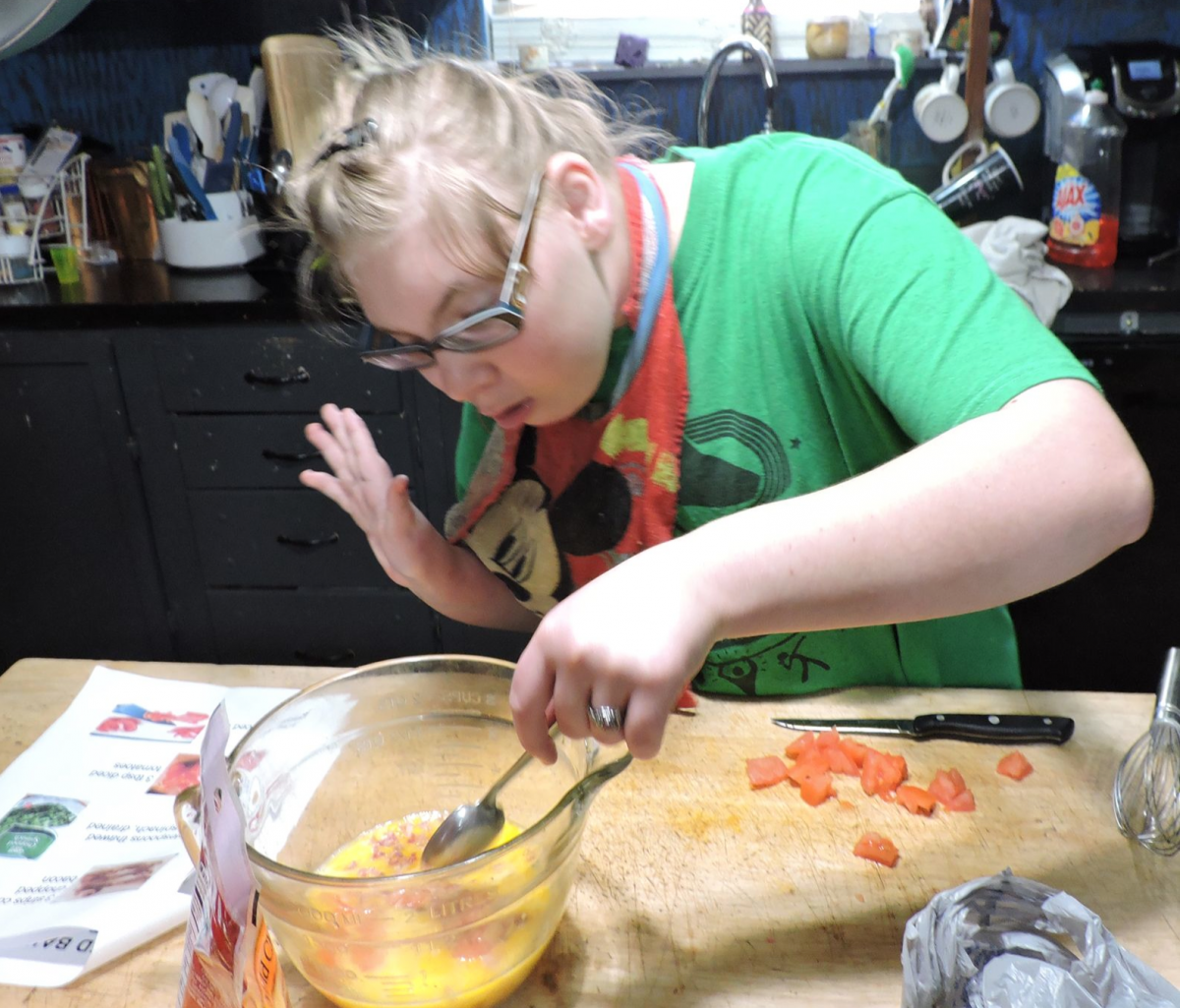A teenage girl stirs ingredients in a mixing bowl