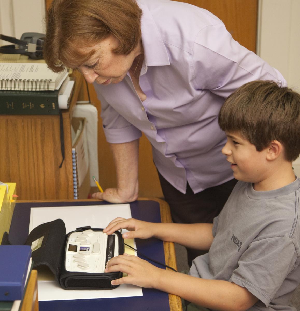 student and teacher using brailler