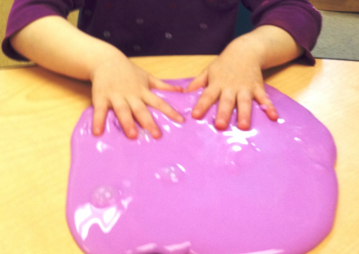 A young child's fingers manipulate clay.