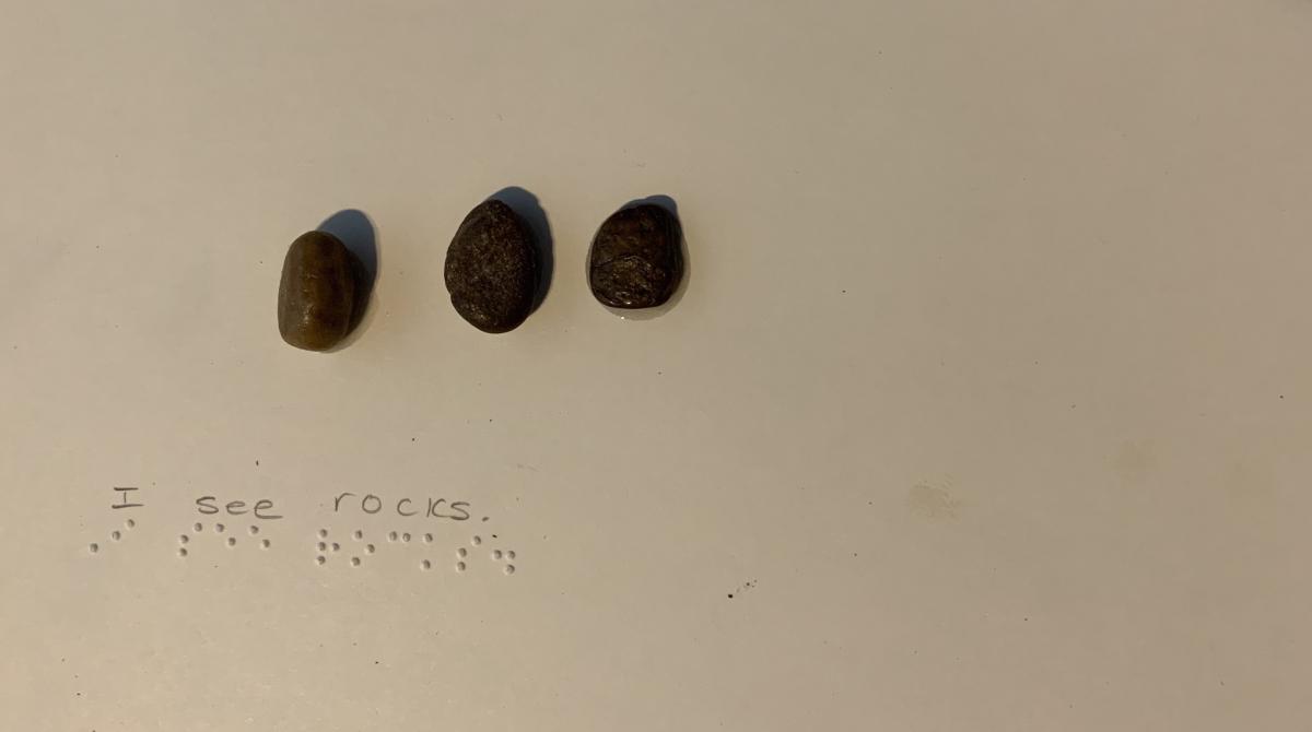 3 small stones with braille text "I see rocks."