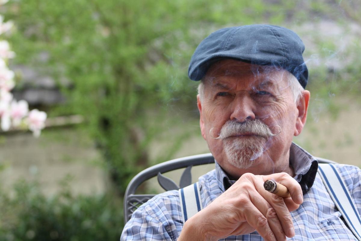 An older man holds a cigar
