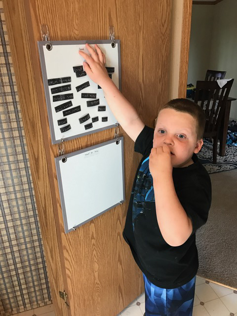 Liam moving grocery items on the magnetic board