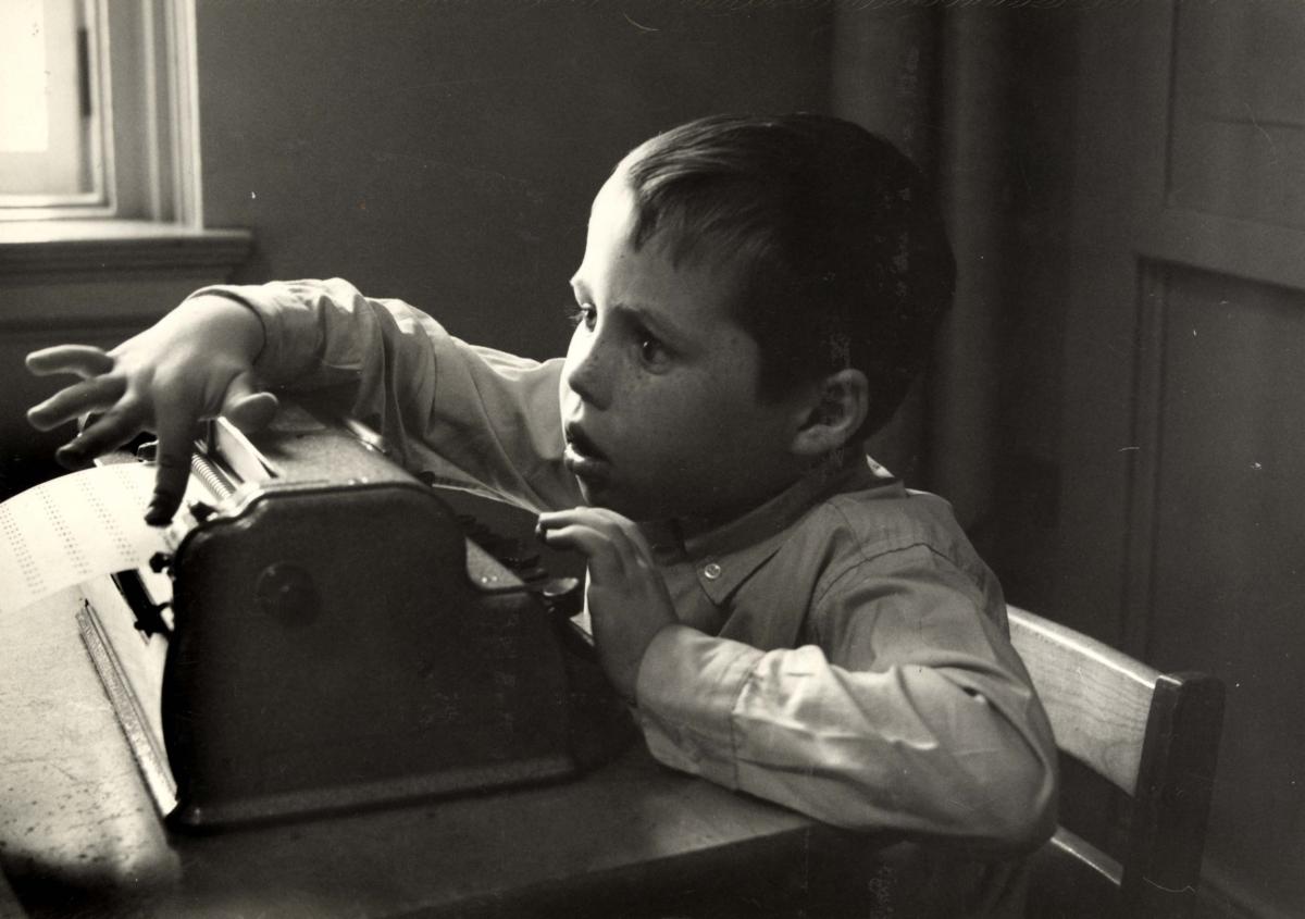 Black and white photo of a young boy using a Perkins brailler