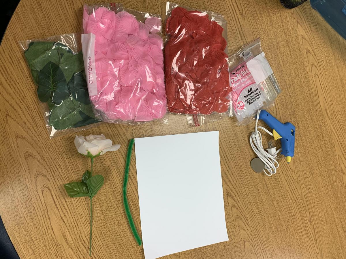 Materials for making tactile flowers, including petals, stem, paper, and glue gun
