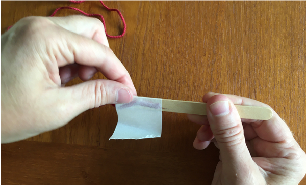 Placing masking tape on popsicle stick