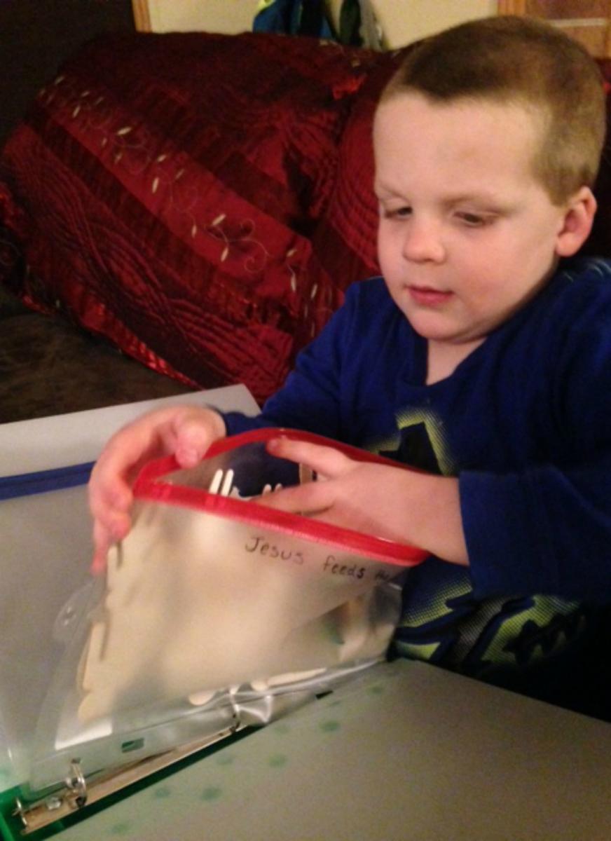 A boy examines wooden figures in plastic pencil bag