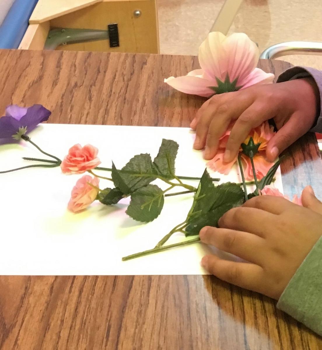 child's hands exploring the fake flowers