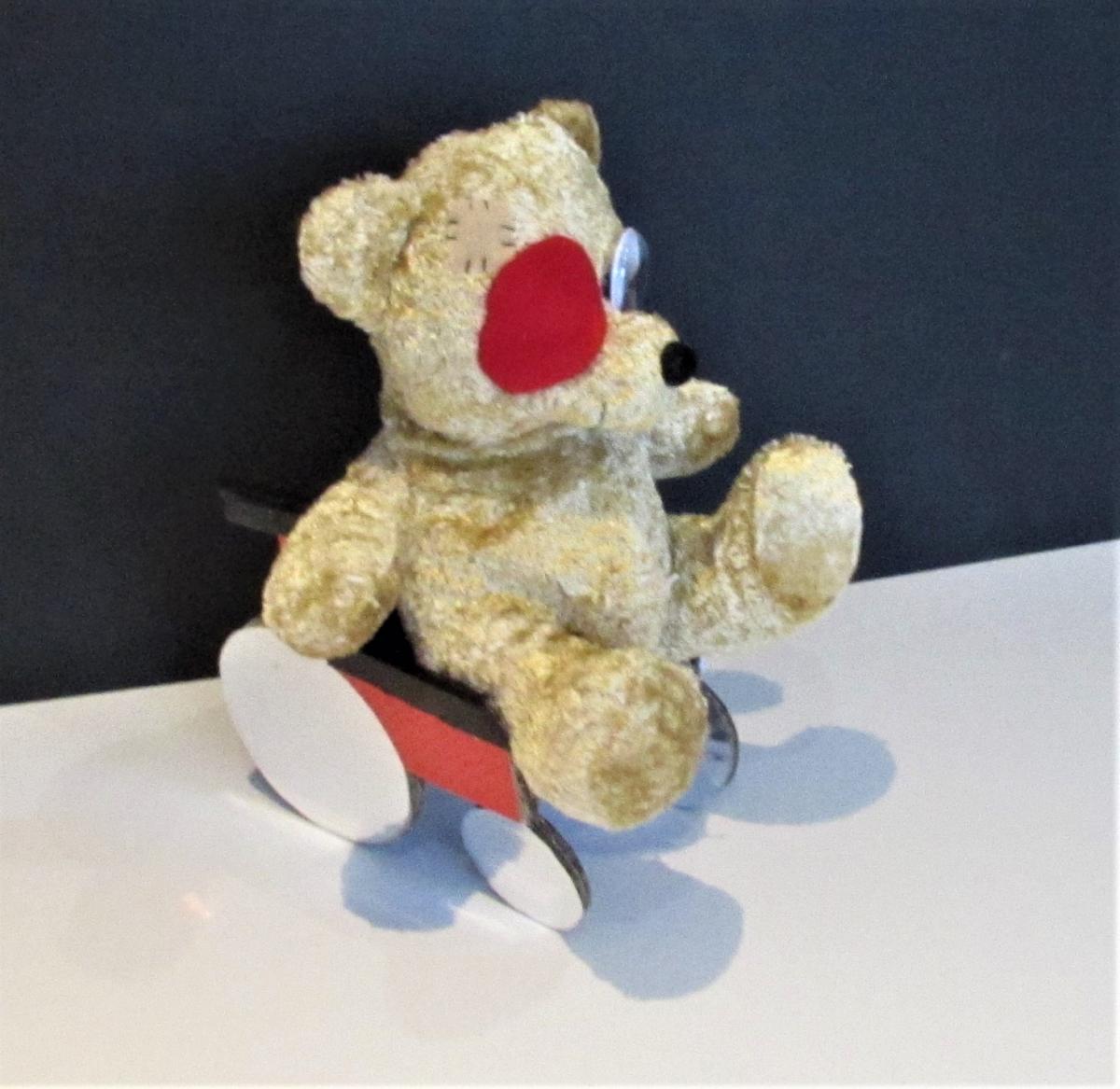teddy bear with eye patch sitting in cardboard wheelchair