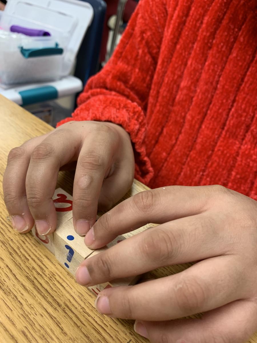 Student reading the braille labels on wooden blocks