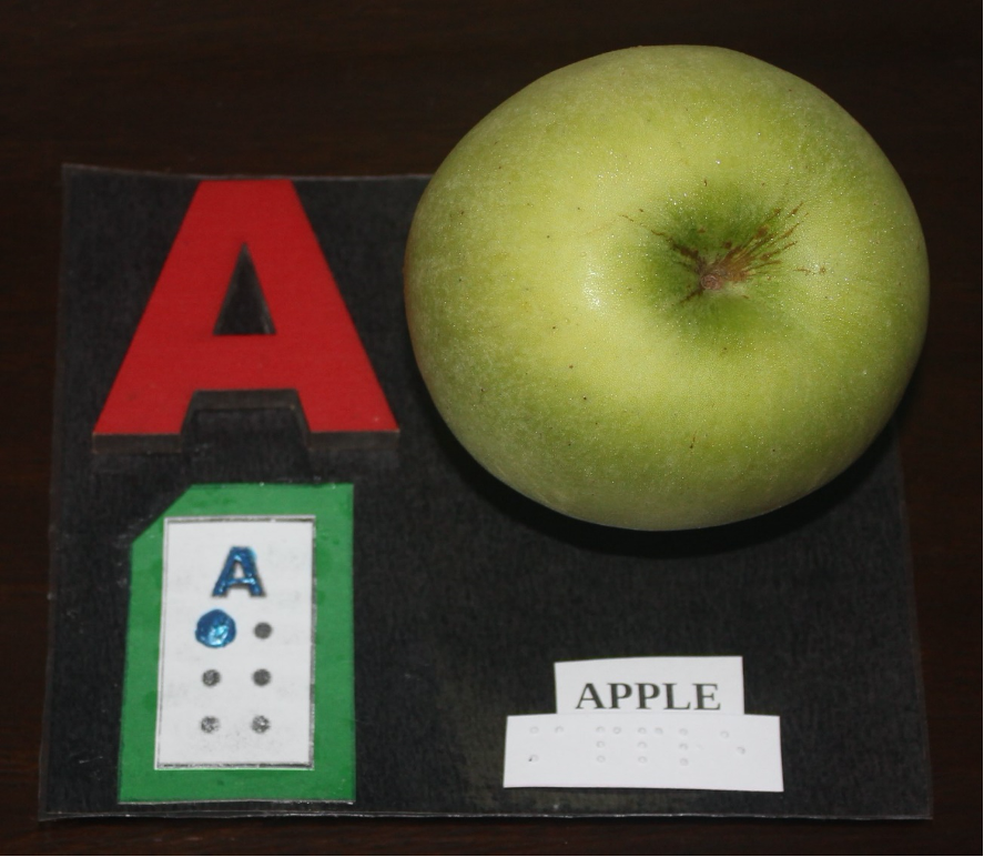 Letter "A" written in print with corresponding braille and an apple.