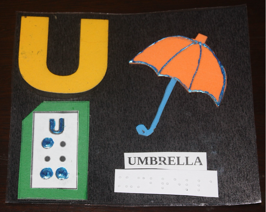 Letter "U" written in print with corresponding braille and a paper cutout of an umbrella