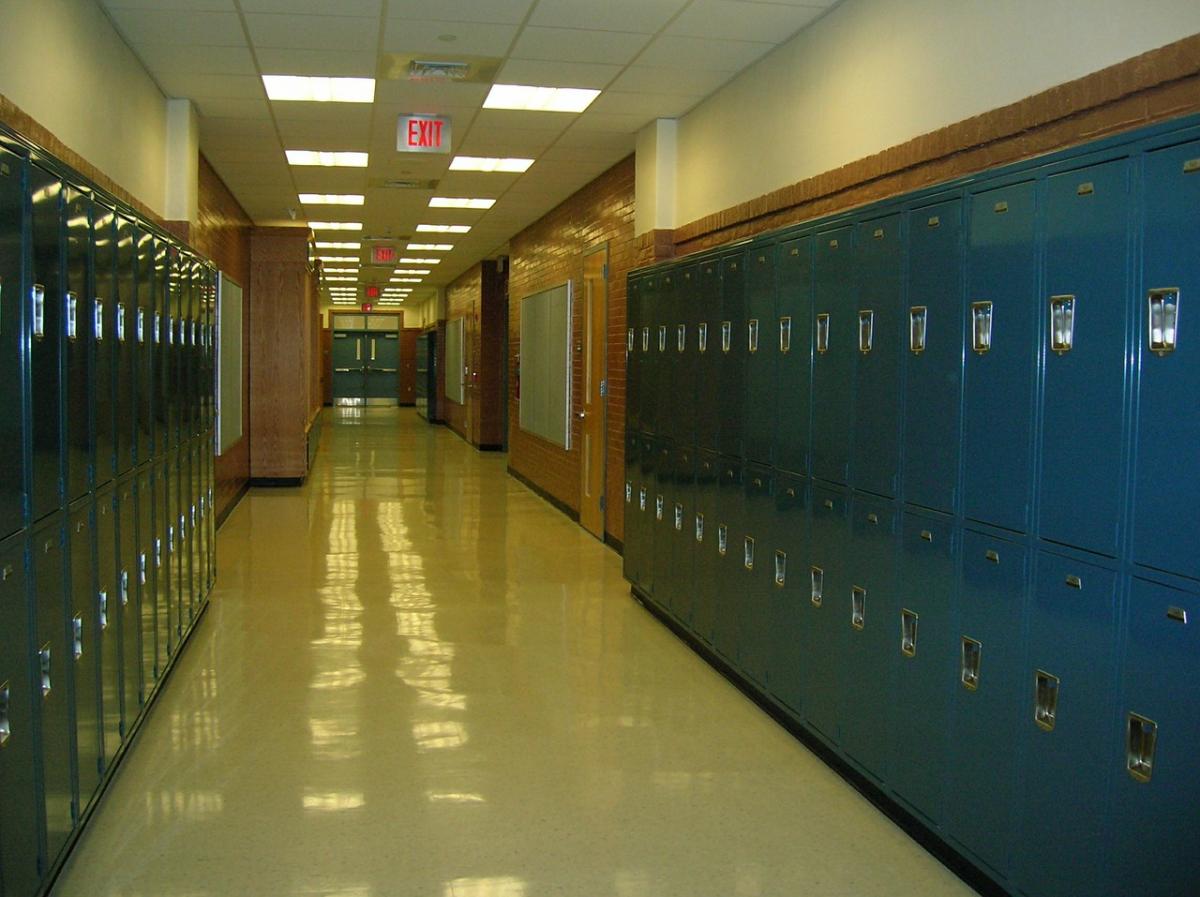 Long school hallway with lockers on side and overhead lighting with glare.