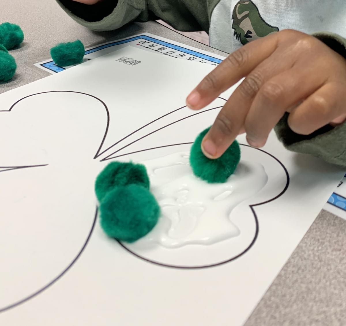 Dipping green pompom in glue
