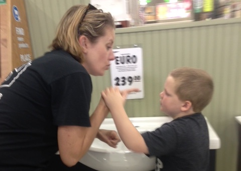 An intervener uses tactile sign to explore sink with child who is deafblind