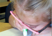 A second grade girl using a colored marker
