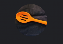Orange slotted spoon on black background