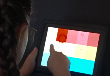 A girl uses an iPad with colored patterns on it.