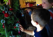 Two boys hanging ornaments on Christmas tree