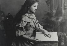 Helen Keller reading a braille book as a young woman