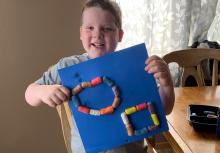 A boy holds up his Magic Nuudle design.