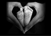 Baby feet with adult hands forming heart shape around them