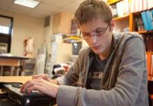 A teenage boy uses a braille notetaker.