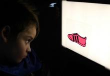 Child looking at lightbox with image of red shoe