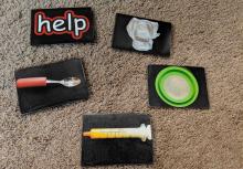 Photo cards on black background: help, spoon, syringe, food bowl, diaper