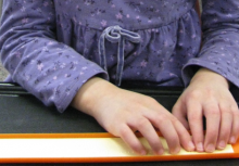 Child's hands reading a line of braille
