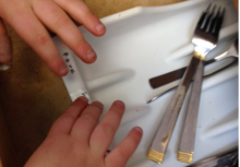 Hands reading braille fork label on silverware drawer