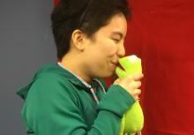 Teen age girl holding Kermit the frog near her mouth