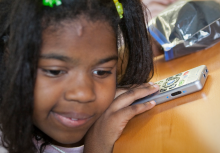 A young girl uses a Braille Port Plus from APH.