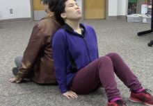 two people sitting on the floor leaning back-to-back