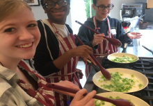 Students stirring vegetables on the stovetop.