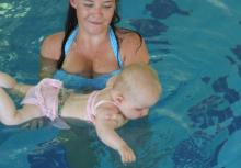 woman holds baby in pool