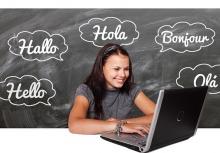 Teen student on laptop with chalkboard background saying hello in various languages