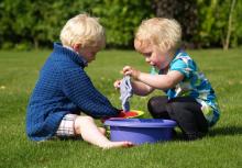 Two young children sitting outside with water play