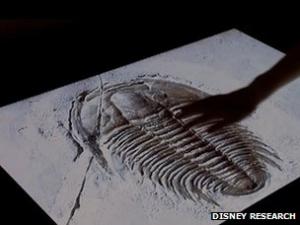 A hand touches a touchscreen of a trilobite