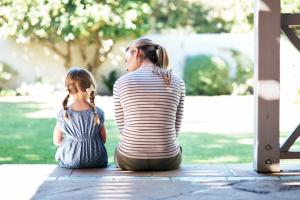 Child sits next to a female adult on the steps