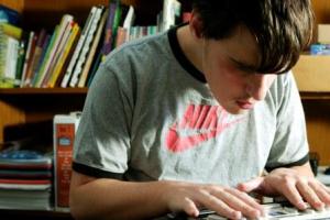 A teenage boy uses a Braille Note.