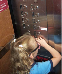Child exploring braille numbers in an elevator