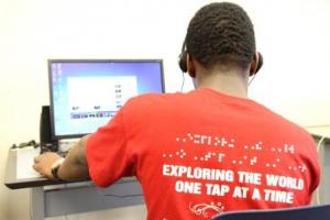 A teenage boy sits at a computer.