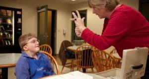 Teacher signs to student while working on money activity.